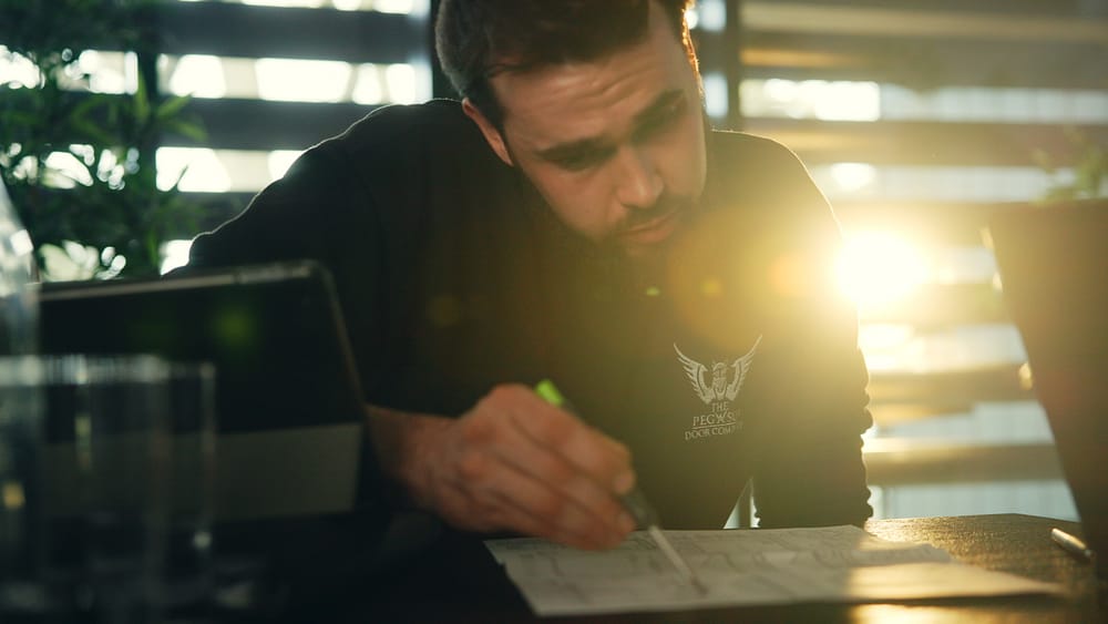 A man looking over plans with a bright sunny light behind him
