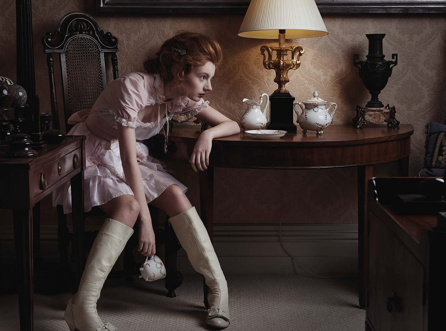 Girl in a black dress sitting on a sofa in an opulent house