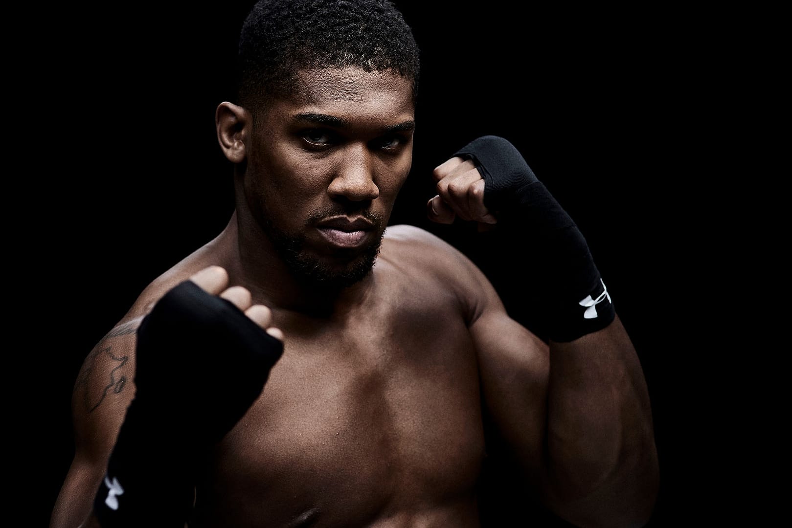 Boxer Anthony Joshua photographed on a black background in a sparing pose