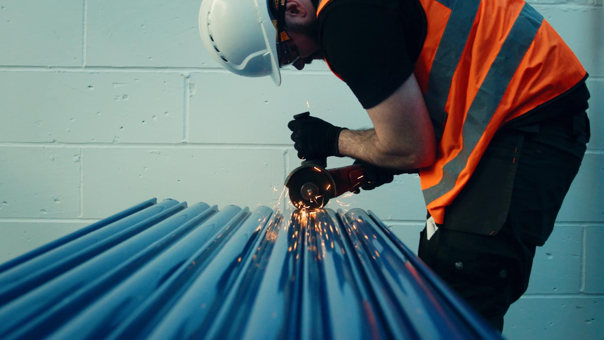 An engineer cutting down metal slates, sparks flying