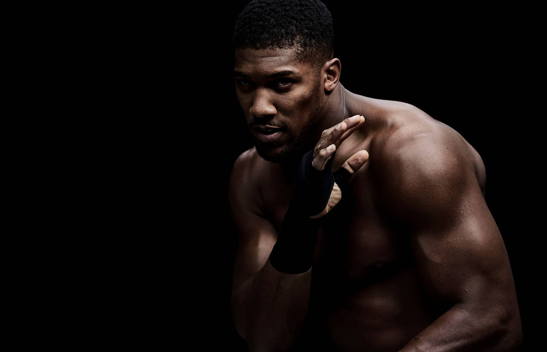 Boxer Anthony Joshua photographed on a black background in a sparing pose